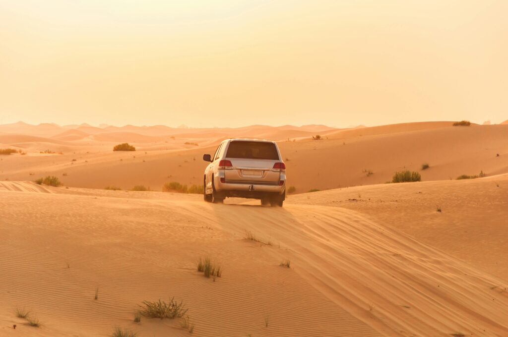 pexels-photo-3684847-3684847 A white SUV driving through the sand dunes of the Arabian desert at sunset, capturing adventure and solitude.