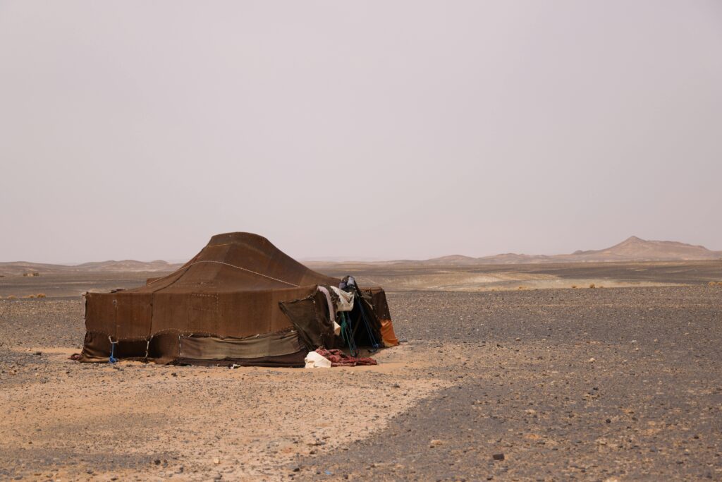pexels-photo-18742774-18742774 Traditional tent in a vast, arid desert landscape under a clear sky, depicting isolation and survival.