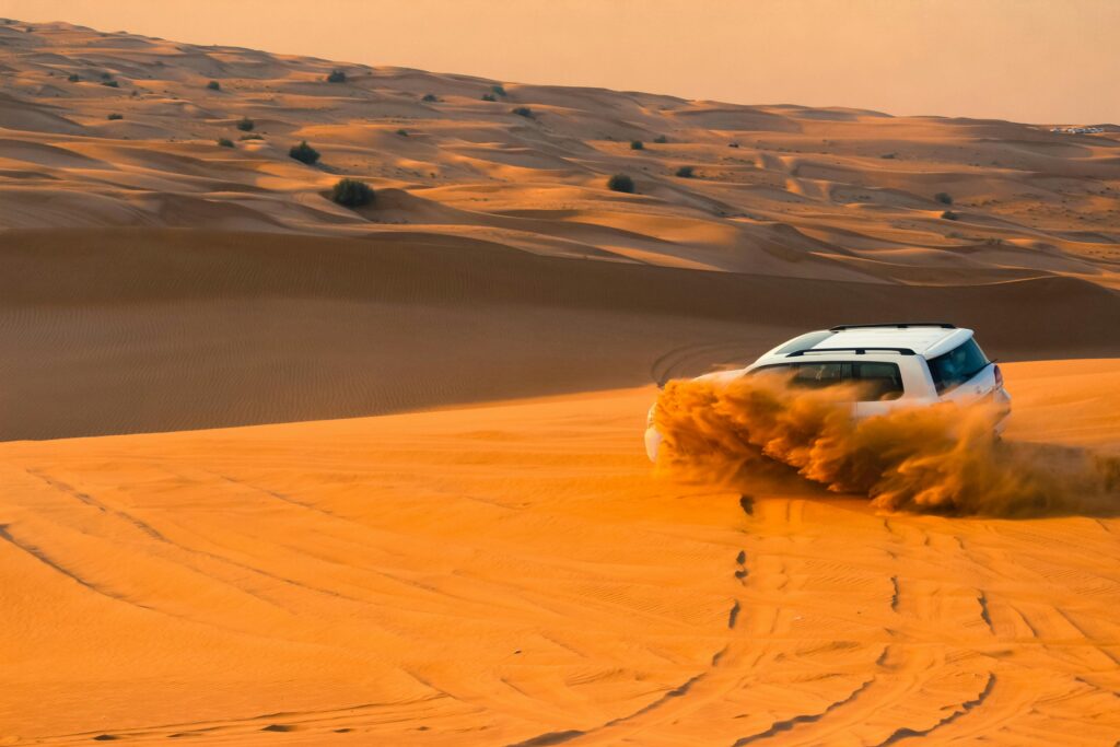 pexels-photo-2417260-2417260 A thrilling SUV driving through the sand dunes of Dubai's desert landscape at sunset.